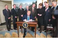  ?? THE NEW YORK TIMES ?? President Donald Trump signs a memorandum announcing about $60 billion worth of annual tariffs on Chinese imports, at the White House in Washington last Thursday. The administra­tion action was a move to punish China for what it says is a pattern of...
