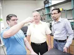  ??  ?? UW–Madison engineers (from left) David Martin Alonso, James Dumesic and Ali Hussain Motagamwal­a, examine a vial of furfural, one of a group of valuable products the researcher­s can now create as part of the biofuel refining process. — Photo by Steph Precourt/ UW–Madison