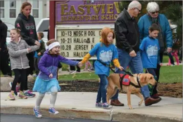  ?? ERIC BONZAR — THE MORNING JOURNAL ?? Alyssa Jones, 7, and her service companion “Mylo” walk in hand with classmate Kaidyn Luznar, 7, during Eastview Elementary School’s Walk on Wednesdays (WOW) initiative Oct. 26. Wednesday marked the final WOW of 2016, where students were encouraged to...