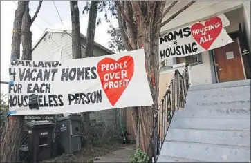  ?? Jeff Chiu Associated Press ?? BANNERS ARE POSTED outside the house that was occupied by homeless women last week in West Oakland. Under a deal reached with a Redondo Beach firm, the squatters will be allowed to purchase the home.