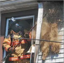  ?? PETE BANNAN — DIGITAL FIRST MEDIA ?? A firefighte­r wearing breathing equipment pulls down insulation and roofing material as he searches for hidden fire at a house fire in the 600 block of Coates Street in Coatesvill­e Monday morning. Two unoccupied homes were seriously damaged in the...