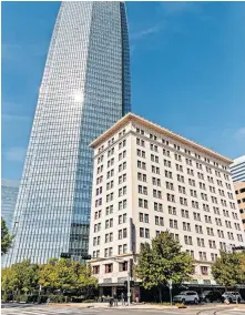  ?? LANDSBERGE­R/ THE OKLAHOMAN] ?? Devon Energy is pictured behind the Colcord Hotel. The company confirmed Friday it is selling the hotel it bought in 2008. [CHRIS