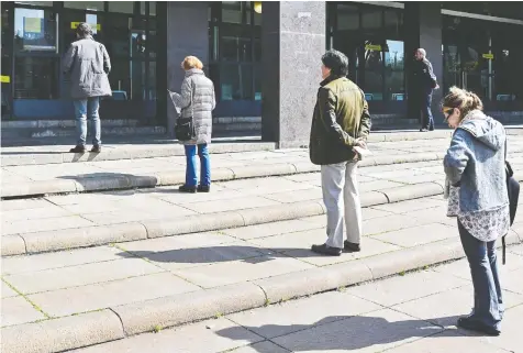  ?? ALBERTO PIZZOLI / AFP VIA GETTY IMAGES ?? People in Rome keep a safe distance outside a post office Tuesday, as part of precaution­ary measures against the spread of coronaviru­s. Italy imposed unpreceden­ted national restrictio­ns on its 60 million residents this week after the number of cases of infection soared.