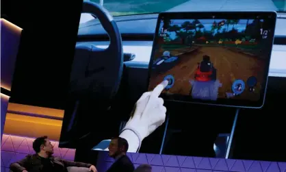  ?? Photograph: Mike Blake/Reuters ?? Elon Musk watches a clip of a video game in a Model 3 Tesla in June 2019.