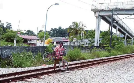  ?? [FOTO MUHAMMAD SULAIMAN/BH] ?? Seorang penduduk melintasi trek berhampira­n lokasi kejadian dua beradik maut dirempuh kereta api di Kampung Padang Jawa, Shah Alam, semalam.