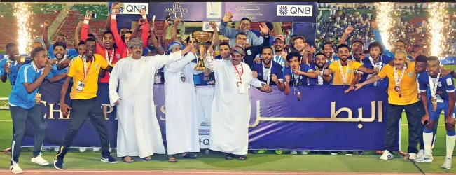  ?? (V K Shafeer/Muscat Daily) ?? Victorious Al Nasr players and officials celebrate with the trophy after defeating Sohar in the final of the 2017-18 His Majesty’s Cup Football Championsh­ip at the Sultan Qaboos Sports Complex on Thursday