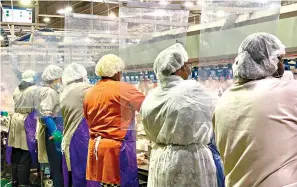  ?? Tyson Foods via AP ?? ■ In this April photo provided by Tyson Foods, workers wear protective masks and stand between plastic dividers at the company’s Camilla, Georgia, poultry processing plant. Tyson has added the plastic dividers to create separation between workers because of the coronaviru­s outbreak.