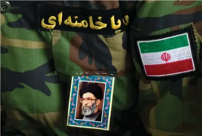  ?? (Reuters) ?? A MAN wearing an Iranian Revolution­ary Guard uniform sports a portrait of Iran’s Supreme Leader Ayatollah Ali Khamenei.