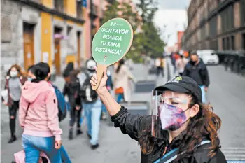  ?? PEDRO PARDO/GETTY-AFP ?? A woman holds a sign reading “Please keep your safety distance” in Mexico City, where mandates are often flouted.