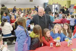  ?? ?? Monsignor Robert Weiss talks with students and staff of St. Rose of Lima parochial school during his retirement celebratio­n at the school.