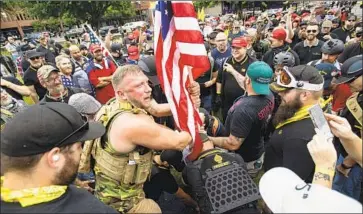  ?? Noah Berger Associated Press ?? THE PROUD BOYS and other right-wing groups plant a U.S. f lag in a Portland park on Saturday. Antifa counterpro­testers were largely kept apart, but the situation was reportedly still volatile as evening neared.