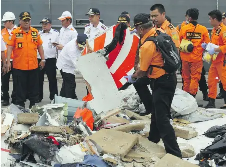  ?? BINSAR BAKARA, AP ?? A rescuer inspects a fragment of the Lion Air Boeing 737 jet retrieved from the Java Sea on Tuesday, along with other debris.