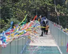  ?? ZHU LIXIN / CHINA DAILY ?? A tourist stops on a bridge to enjoy the scenery in Jingxian county, Anhui province on April 12. The bridge, built of steel and glass, is over a stream and leads to a mountain trail.