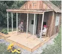  ??  ?? Grandkids Claudia and Neil take in the view from the front porch of the playhouse Mark built for them.