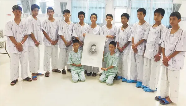  ?? Photo / AP ?? The Wild Boars football team pose at the hospital in Chiang Rai with a sketch of the Thai Navy Seal diver who died while trying to rescue them.