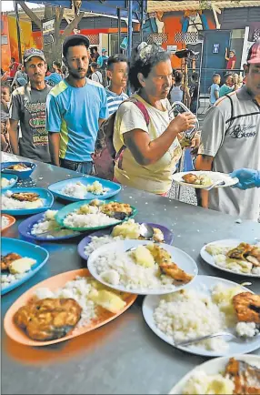  ??  ?? EMERGENCIA. Voluntario­s reparten platos de comida en Cúcuta, Colombia, a pocos kilómetros de la frontera venezolana.