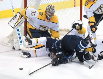  ?? CP PHOTO ?? Mark Scheifele of the Winnipeg Jets gets buried by Ryan Ellis of the Nashville Predators in front of goaltender Pekka Rinne during Tuesday night’s game in Winnipeg.