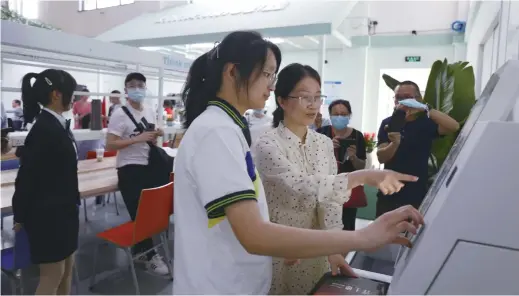  ??  ?? A teacher gives guidance to a student when she borrows a book. The convenient borrowing system enables readers to borrow books just by swiping the library card and scanning the book’s barcode. Students can borrow up to 10 books at one time. — All photos by courtesy of Hangzhou Library Yuexiang Branch