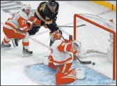  ?? The Associated Press Mary Schwalm ?? Bruins right wing Garnet Hathaway scores past Red Wings goalie Magnus Hellberg and center Dylan Larkin in Boston’s win Saturday at TD Garden.