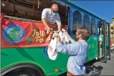  ?? Dan Watson/ The Signal ?? (Left) Santa Clarita Transit Road Supervisor Keith Carr organizes boxes and bags of donations during the Santa Clarita Jolly Trolley Food Drive at Westfield Valencia Town Center, one of its five stops Saturday. (Above) Carr, aboard the Jolly Trolley, and Administra­tive Analyst Alex Porlier collect donated food at the mall for the SCV Food Pantry.