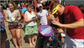  ?? PAUL POST — PPOST@DIGITALFIR­STMEDIA.COM ?? National Astronomy Foundation employee Benjamin Palmer, right, helps Saratoga Race Course fans view the eclipse through a special telescope.