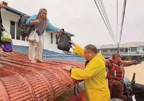  ?? (Foto FB Datuk Seri Tiong King Sing) ?? King Sing membantu mangsa banjir yang naik ke bumbung rumah untuk berpindah ke pusat pemindahan.