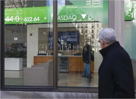  ?? NICOLAUS CZARNECKI / HERALD STAFF ?? THAT SINKING FEELING: A pedestrian Friday passes the Fidelity office on Congress Street downtown, where a crawler shows markets posting losses. At top, traders at the New York Stock Exchange wrap up the worst week since the Great Recession of 2008.