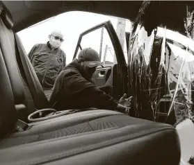  ?? Seth Wenig / Associated Press ?? Uber driver Luis Hidalgo, left, watches as Joel Rios installs a plastic barrier in his car to protect himself and his passengers from the coronaviru­s in New York.