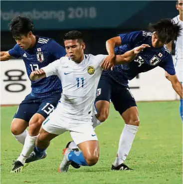  ??  ?? Sandwiched: Malaysia’s Safawi Rasid (centre) fighting for the ball with Japan’s Iwasaki Yuto (left) and Matsumoto Taishi in the round of 16 match at the Patriot Candrabhag­a Stadium in Bekasi yesterday.