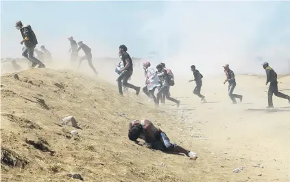  ?? PHOTO: REUTERS ?? Under siege . . . Palestinia­n demonstrat­ors run from tear gas fired by Israeli forces during a protest at the IsraelGaza border in the southern Gaza Strip last week.