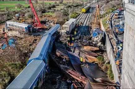  ?? Angelos Tzortzinis / The New York Times ?? Workers remove a destroyed train carriage, left, and other debris at the train collision site near the Vale of Tempe, a gorge near Larissa in northern Greece, on Friday. The fire service in Greece started winding down a search on Friday at the scene of the country’s deadliest train crash on record.