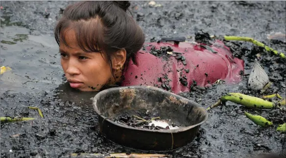  ?? ?? A woman searches for nails and other metal scraps from remains of burned houses that were gutted during a fire at a poor bayside village in the district of Tondo, Manila, Philippine­s