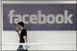  ?? THE ASSOCIATED PRESS ?? Facebook employee walks past a sign at Facebook headquarte­rs in Menlo Park, Calif.