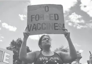  ?? NANCY LANE/AP ?? Paulette McGuinness holds up a sign during a protest against mandatory flu vaccinatio­ns outside the Massachuse­tts State House on Aug. 30 in Boston. Public health authoritie­s say flu shots are especially important this year to avoid overburden­ing the health system. amid the coronaviru­s pandemic.