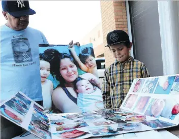  ?? MICHELLE BERG ?? Dan Longman and Dan Junior Longman look at a collage of photos of baby Nikosis outside provincial court in Saskatoon while waiting to hear the sentencing dates set for the teen who killed baby Nikosis a year ago.