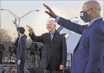  ?? Chip Somodevill­a Getty I mages ?? PRESIDENT- ELECT Joe Biden, center, acknowledg­es supporters at an Atlanta campaign rally with fellow Democrats Jon Ossoff, left, and the Rev. Raphael Warnock, both candidates for seats in the U. S. Senate.