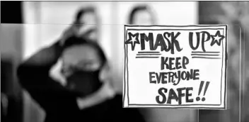  ?? AP Photo/Mat Slocum ?? In this Nov. 17 file photo, manager Yllka Murati waits for a delivery driver to pick up takeout orders behind a partition displaying a sign to remind customers to wear a mask, at the Penrose Diner, in south Philadelph­ia.