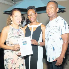  ?? PHOTO BY JANET SILVERA ?? Winner of a six days, five nights stay at Couples Resort and roundtrip tickets from Jetblue, Rose Green (centre) accepts her prize from host Sheree Sparkes and Gary Williams, founder and chairman of Children of Jamaica Outreach, last Saturday night.