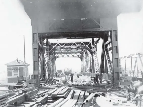  ?? CITY OF VICTORIA ARCHIVES, IMAGE M00314 ?? Workers carry wooden decking onto the Johnson Street Bridge during constructi­on, c. 1922.