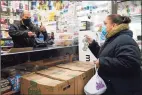  ?? Associated Press ?? Bodega owner Francisco Marte, left, assists a customer with her purchase Feb. 10 in the Bronx, N. Y. Marte heads up the Bodega and Small Business Group, which represents bodegas in New York, and said he has been lobbying local officials to set aside appointmen­ts for bodega workers, many of whom are unaware they are eligible.