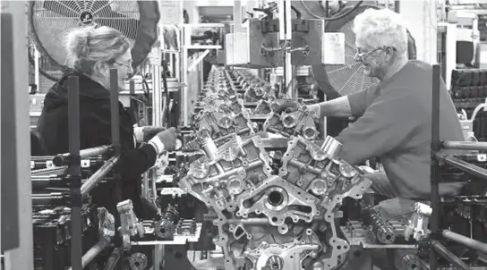  ??  ?? Ford assembly line employees work on 3500 Duramax engine as they move along the assembly line at the Ford Lima Engine Plant in Lima, Ohio, March 28, 2014.