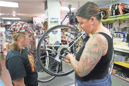  ?? MICHAEL SEARS / MILWAUKEE JOURNAL SENTINEL ?? Katie Jesse (right) of Milwaukee makes adjustment­s to her bike as Truly Spoken Cycles mechanic Heather Sewrey explains a how to fix a shifting problem. Ladies Revolution MKE held a do-it-yourself bike repair clinic for women at Truly Spoken Cycles. See...