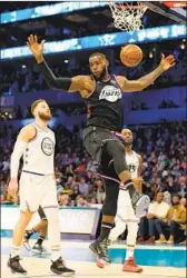  ?? Streeter Lecka Getty Images ?? LeBRON JAMES dunks between Blake Griffin, left, and Kemba Walker during the All-Star game.