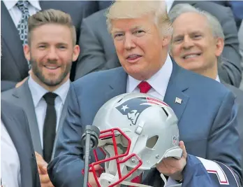  ??  ?? US President Donald Trump holds a New England Patriots helmet as Patriots head coach Bill Belichick and Patriots player Julian Edelman, rear, look on during a ceremony at the White House.