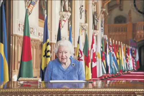  ?? PICTURE: STEVE PARSONS/PA WIRE. ?? BY THE BOOK: The Queen signs her annual Commonweal­th Day Message yesterday in St George’s Hall at Windsor Castle, where she is staying during lockdown.