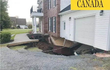  ?? PAUL MAYNARD / THE CANADIAN PRESS ?? A sinkhole appeared under this Falmouth, N.S., house on Sunday. Officials say the family is safe, but the building is expected to collapse soon.