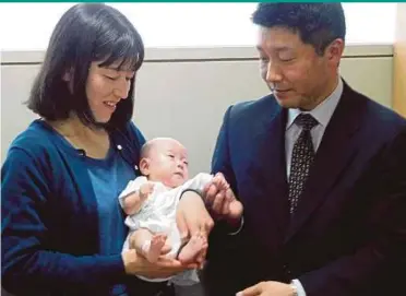  ??  ?? Six-month-old Ryusuke Sekiya (centre) with his parents one day before his scheduled discharge from hospital in Azumino, Nagano prefecture, yesterday.