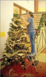  ?? Lynn Atkins/The Weekly Vista ?? Tiffany Hastings of the Cooper Elementary Parent Teacher Organizati­on adjusts the star on a tree in the school’s lobby. The PTO is one of the organizati­ons that help ensure all Cooper kids enjoy a merry Christmas.