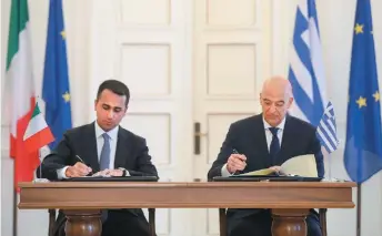  ??  ?? Greek Foreign Minister Nikos Dendias (r) and his Italian counterpar­t Luigi Di Maio sign an agreement demarcatin­g the maritime borders between the two countries, following a meeting in Athens, on June 9.