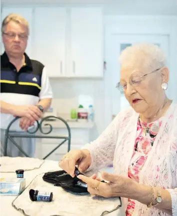  ?? TROY FLEECE ?? Petronella Hofenk tests her blood sugar level as her son Rick looks on. The Hofenks are upset with a 2015 change to the drug plan that limits the number of blood glucose test strips that are covered under the provincial drug plan. Petronella Hofenk, a...
